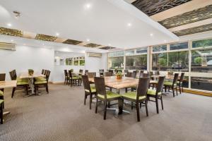 uma sala de jantar com mesas, cadeiras e janelas em Park Motor Inn em Toowoomba