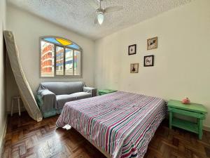 a bedroom with a bed and a couch and a window at Apartamento a beira-mar in Capão da Canoa