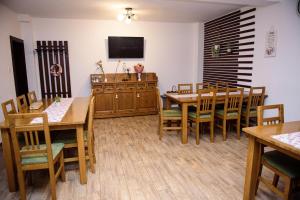 una sala da pranzo con tavoli e sedie in legno di Vendégváró Panzió a Lupeni