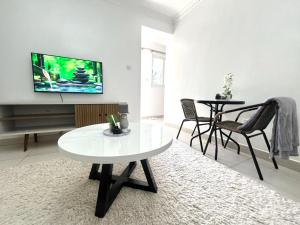 ナイロビにあるNeema Executive Suites With Balcony Near Prestige Mallのテーブルと壁にテレビが置かれたリビングルーム