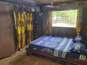 a bed in a room with a window and skis at Mananambal Beach Huts - Family hut in Nagbalaye +26 photos
