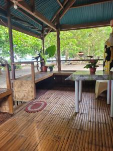 a pavilion with a table and plants on a wooden floor at Mananambal Beach Huts - Family hut in Nagbalaye