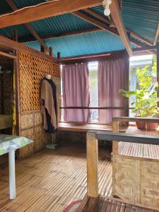 a room with a wooden floor and a balcony at Mananambal Beach Huts - Family hut in Nagbalaye