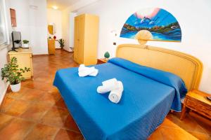 a bedroom with a blue bed with towels on it at Le Tartarughe Aparthotel in Letojanni