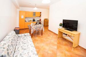 a living room with a couch and a television and a kitchen at Le Tartarughe Aparthotel in Letojanni