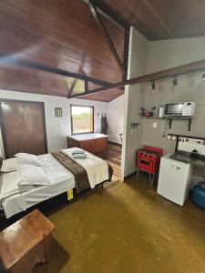 a bedroom with a large bed and a kitchen at Chalés Lavras de Minas - Brasil in Lavras Novas