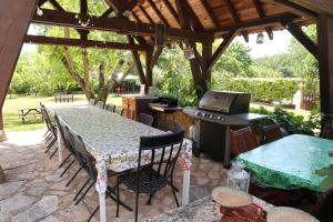 an outdoor patio with a table and a stove at Gites le Sud, La Petite Grange in Puybrun