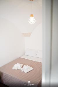 a bed with two white towels on top of it at Vicolo Home in Putignano