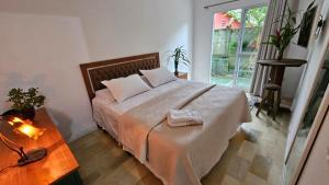 um quarto com uma cama, uma mesa e uma janela em Quarto Pitangueiras em Florianópolis