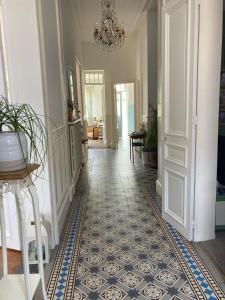 a hallway with a tile floor and a chandelier at Maison Dentelle in Caudry