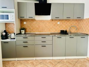 a kitchen with white cabinets and a sink at Szabo Laszlo Vip Apartman in Hajdúszoboszló