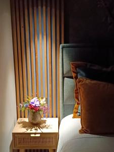 a vase of flowers on a table next to a bed at Filoxenia Luxury Apartment in Nafplio