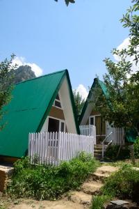 uma casa com um telhado verde e uma cerca branca em Enthralling Escapes Nature Stay and Trek em Manali mais 33 fotografias