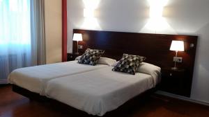 a bedroom with a large bed with two pillows at Hotel La Isla in Colunga