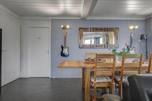 un comedor con una mesa y una guitarra en la pared en Vakantiehuis Rumah Kami - Julianadorp aan Zee, en Julianadorp