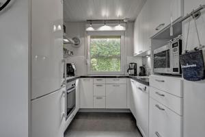 Una cocina blanca con electrodomésticos blancos y una ventana. en Vakantiehuis Rumah Kami - Julianadorp aan Zee, en Julianadorp