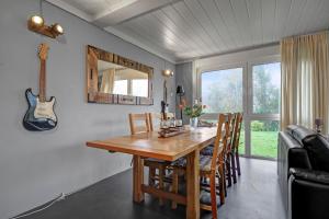 Una mesa de comedor con sillas y una guitarra en la pared. en Vakantiehuis Rumah Kami - Julianadorp aan Zee, en Julianadorp