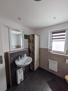 a bathroom with a sink and a refrigerator at fewoflagmeier Meidelstetten I Maisonetten Wohnung Alb in Hohenstein +14 photos