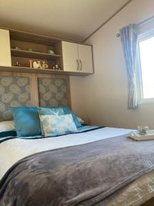 ein Schlafzimmer mit einem Bett mit blauen Kissen und einem Fenster in der Unterkunft Tattershall Lakes Luxury Hot Tub Breaks in Tattershall + 14 Fotos