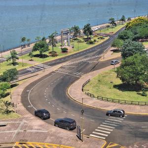 a street with cars driving down a road next to the ocean at Ventanas al Rio in Posadas