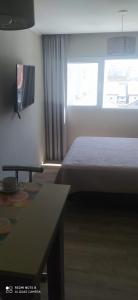 una habitación con una cama y una mesa y una ventana en Casa de playa monoambiente, en Necochea