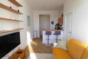 a living room with a yellow couch and a kitchen at Cosy Cocoon Place Massena in Nice