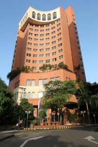 a large brick building with a tree in front of it at Hotel Dann Carlton Cali in Cali