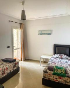 a bedroom with two beds and a table and a window at Golf & sea view appartement in Asilah Marina Golf in Asilah +10 photos