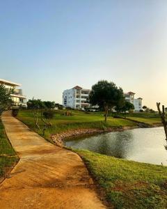 a river in a park with buildings in the background at Golf & sea view appartement in Asilah Marina Golf in Asilah