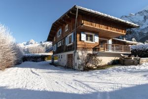 a wooden house in the snow with a snow covered yard at Chalet Des Grands Vanays in Les Houches
