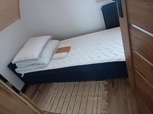a small bed in a small room with white sheets at Noclegi pod 13 Sandomierz in Chwałki