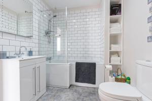 a white bathroom with a tub and a toilet at Stylish 2 Bed Home near Gatwick in Redhill +37 photos