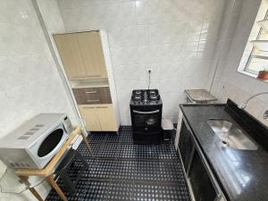 Una pequeña cocina con estufa y fregadero. en Pie en la arena de la playa Tupi, en Samaritá 3 fotos más