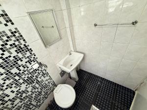 Un baño pequeño con inodoro y lavabo. en Pie en la arena de la playa Tupi, en Samaritá