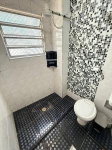 Un baño con inodoro y azulejos blancos y negros. en Pie en la arena de la playa Tupi, en Samaritá