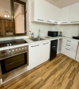 une cuisine avec des armoires blanches, un évier et une cuisinière dans l'établissement Quite and Modern Studio, à Tirana