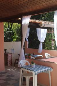 a patio with a table and chairs and curtains at Pousada Korui in Abraão