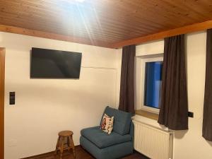 Apartment Lydia في سخلادميخ: غرفة بها كرسي أزرق وتلفزيون بشاشة مسطحة