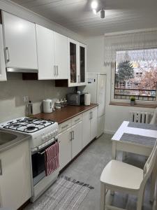 a kitchen with white cabinets and a stove and a table at Apartament Korczaka możliwość wystawiania Faktur, WI-FI in Suwałki