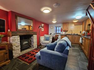 a living room with a blue couch and a stone fireplace at Causeway Cottage in Cartmel