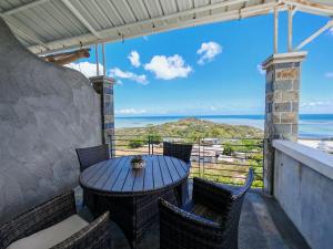 a table and chairs on a balcony with a view of the ocean at Residence Bethel in Rodrigues Island