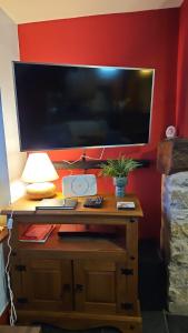 a desk with a large television on a red wall at Causeway Cottage in Cartmel