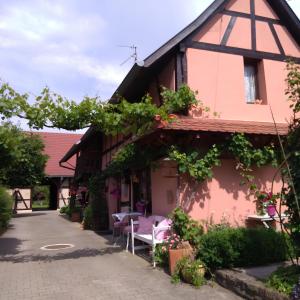 una casa rosa con tavolo e sedie all'esterno di Gite Gabrielle a Blaesheim
