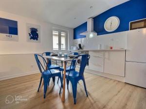 a kitchen with a table and blue chairs in a room at Le Bleuet au cœur de Valence in Valence