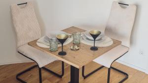 a wooden table with two chairs and a table with glasses at Donau Bliss Linz City Suite in Linz