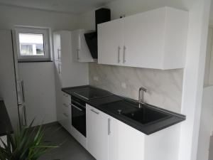 a kitchen with white cabinets and a sink at Allgäu-Ferienwohnung am Bachgrund in Argenbühl +19 photos