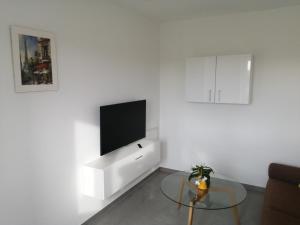 a white living room with a tv and a glass table at Allgäu-Ferienwohnung am Bachgrund in Argenbühl