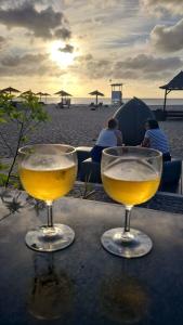 two wine glasses sitting on a table on the beach at Unique Poolside Apartment in Santa Maria