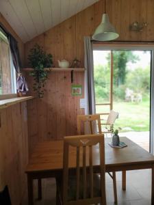 a dining room with a wooden table and chairs at Le Merle Moqueur, maisonnette en bois, Les kabanes en Kreiz Breizh in Rostrenen