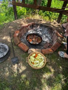 a fire pit with a bowl of food and a bowl of vegetables at Una, Home on river bank in Spilja